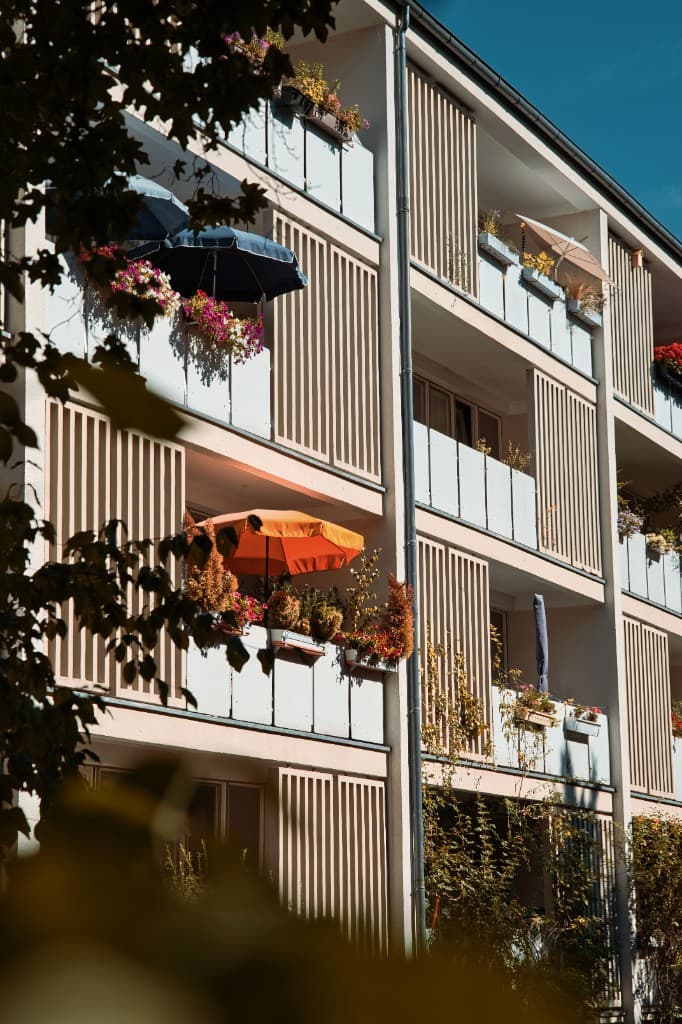 Wohnungshaus mit begrünten Balkonen und Sonnenschirmen
